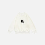 Front view of the beige Number 9 Embroidered Sweatshirt in a gray background