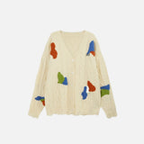 Front view of the apricot Abstract Patch Cable Knit Sweater in a gray background