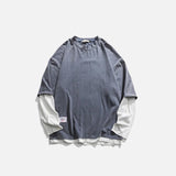 Grey oversized T-shirt layered over white long-sleeve, minimalist streetwear, white background.