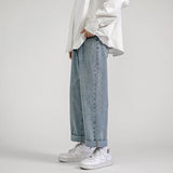 White long-sleeve shirt, wide light blue jeans, white Nike shoes, minimalist background.