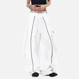 White pants with black piping worn by a person on a white background