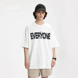 Model wearing the white EVERYONE Oversized T-Shirt in a gray background