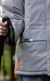 A girl carrying a stick and wearing rain captain jacket