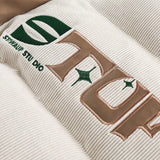 Details showing the embroidery letter print of the beige Corduroy Patchwork Padded Retro Puffer Jacket from DAXUEN