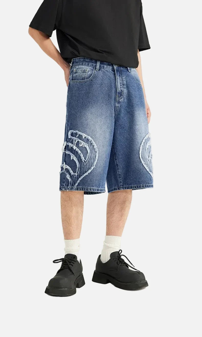 Model wearing the blue Denim Patchwork Shorts in a gray background 