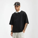 Model wearing the black Placket Polo T-Shirt in a gray background