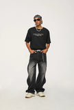 Model wearing the black Baggy Washed Denim Jeans in a gray background 
