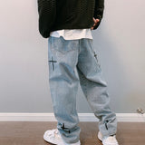 Black textured sweater, white shirt, light blue jeans with crosses, white sneakers, wooden background.