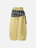 Baggy pale yellow sweatpants featuring an integrated black and white plaid waist wrap with a small pocket and star graphic