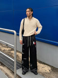 DAXUEN black satin wide-leg pants with bold two-letter graphic — model photo