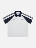 Light grey oversized polo shirt with navy blue raglan sleeves, striped shoulder detailing, and retro chest graphics.