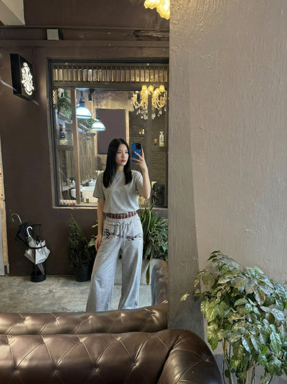 DAXUEN Grey wide-leg sweatpants with musical print and plaid details — model photo